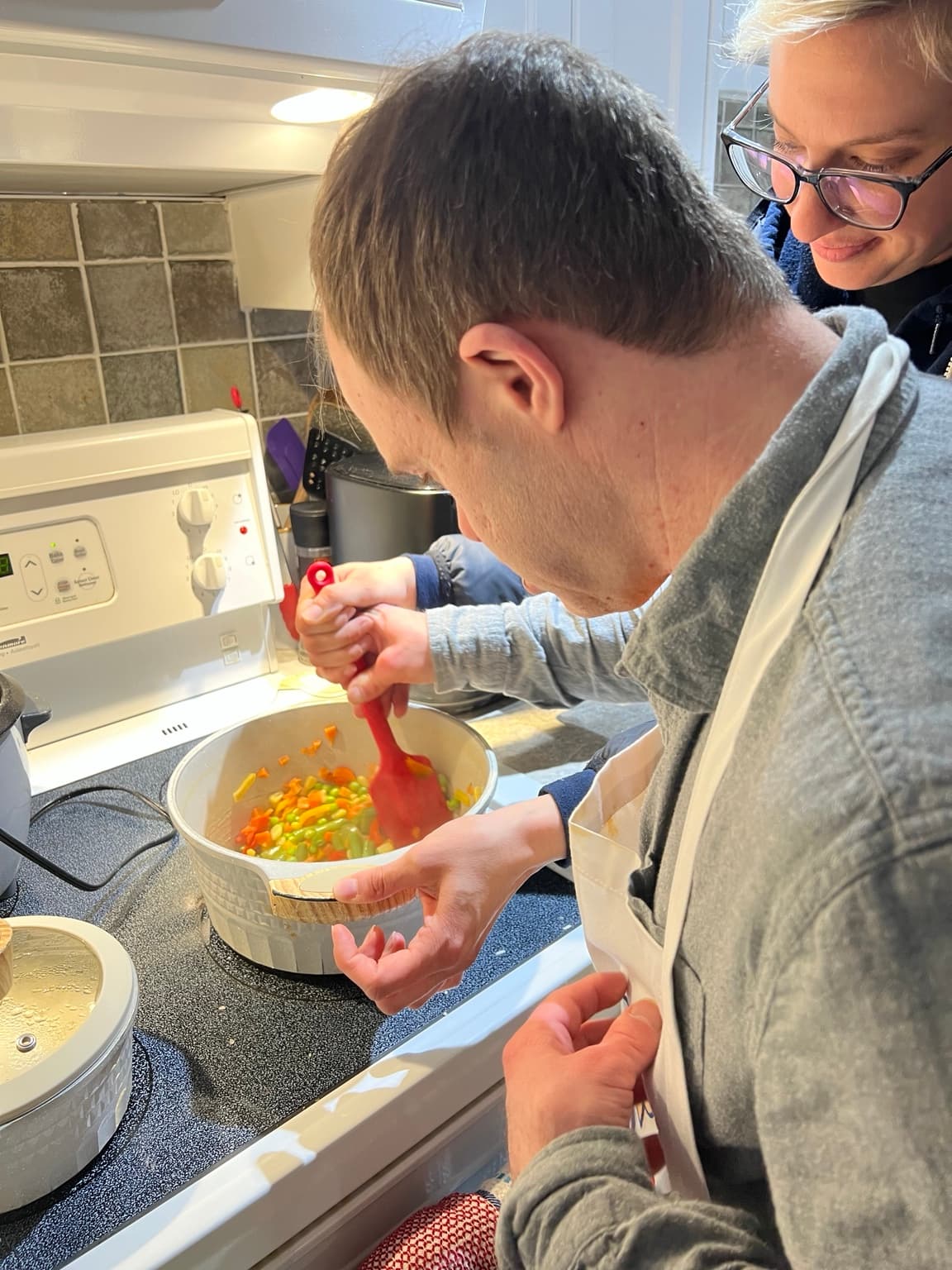 A Catching Stars participant receiving support while helping at the stove.