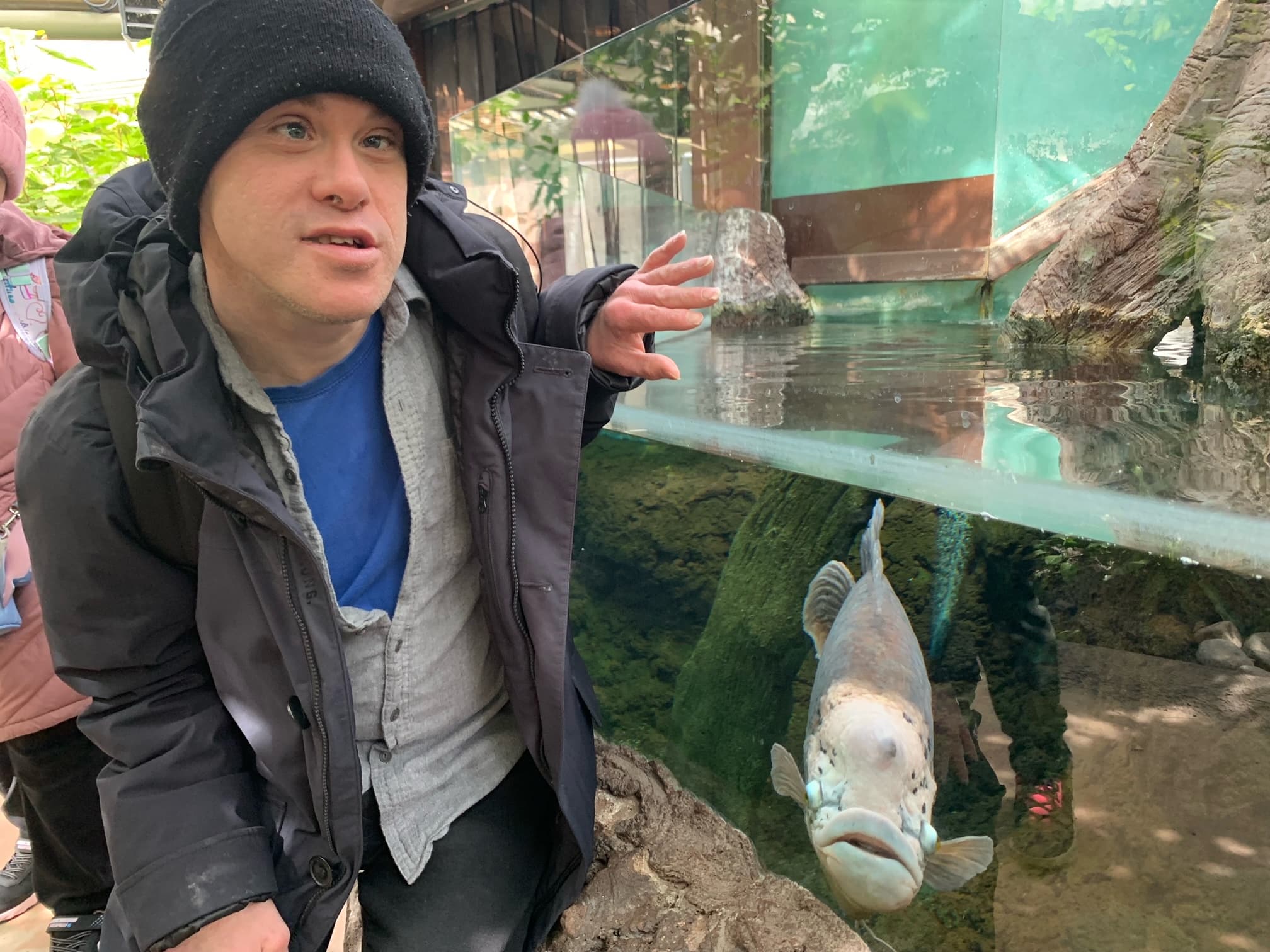 A Catching Stars participant in a supported adult community outing program observing an aquarium exhibit.
