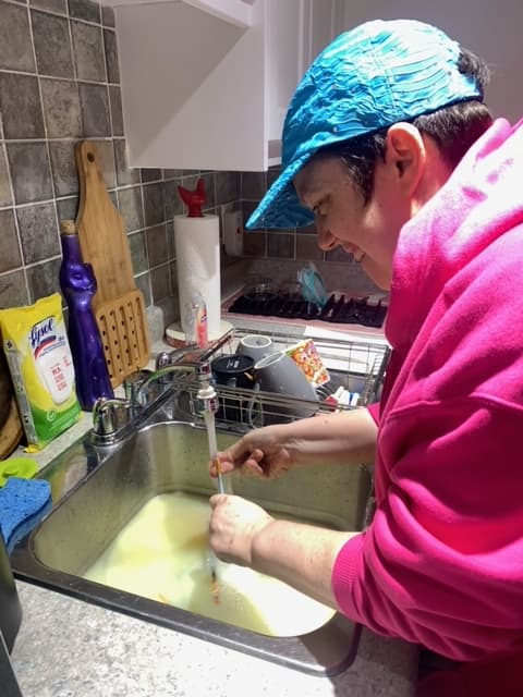 A Catching Stars participant washing dishes as a helping role.