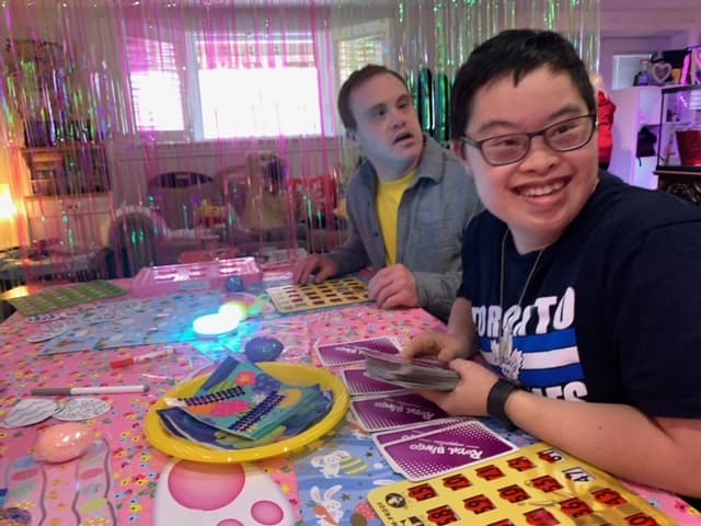 Catching Stars Social Club participants smiling together during a special-needs adult program table activity.